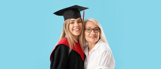 Happy female graduating student with her mother on blue background