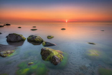 Morze bałtyckie - wschód słońca na plaży Gdynia Orłowo z widokiem na fale i kamieniste...