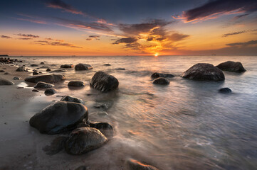 Fototapeta na wymiar Morze bałtyckie - wschód słońca na plaży Gdynia Orłowo z widokiem na fale i kamieniste wybrzeże bałtyku, koło klifu w Orłowie