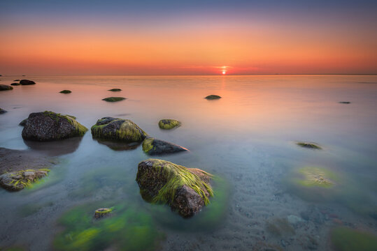 Fototapeta Morze bałtyckie - wschód słońca na plaży Gdynia Orłowo z widokiem na fale i kamieniste wybrzeże bałtyku, koło klifu w Orłowie