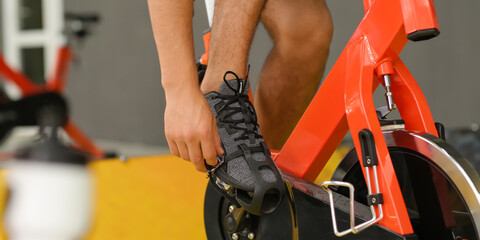 Young man training on exercise bike in gym, closeup