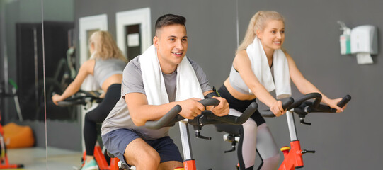 Young people training on exercise bikes in gym