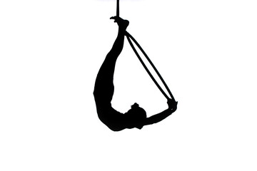 Black silhouette of a young woman gymnast performing on an aerial hoop on a white isolated studio...