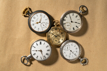 Set of five antique gold and silver American and Swiss pocket watches with markings on beige background. Retro watch with white dials, hands and numbers. Presentation of old vintage round pocket watch