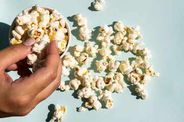 Hand taking salt popcorn from craft paper cup. Concept of cinema or watching TV.
