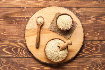 Board with bowls of sesame seeds on wooden background