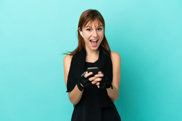 Redhead sport girl isolated on blue background surprised and sending a message