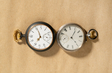 Two of antique silver pocket watches with golden clockwork on beige background. Retro mechanical...