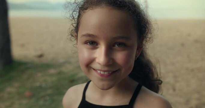 Child smiles while looking at the camera. Girl dream. Face close-up. Happy child in park. Happy girl in rays of the sun. Girl face in beach close-up. Dream girl. Happy face of a child. Beautiful face