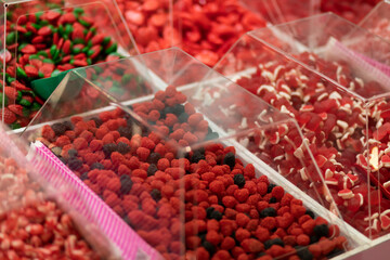 Colorful bright red pink jelly sweets, candy in transparent boxes  on showcase in candy shop. Low sugar fruit gummies, hues come from fruit and veggie juices. Smart healthy living. Horizontal plane