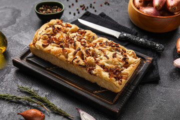 Wooden board with tasty Italian focaccia on dark background