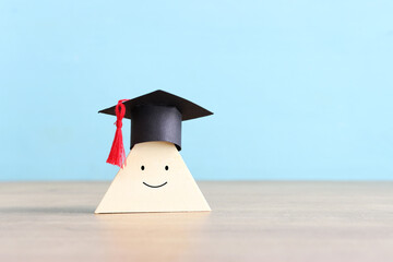 A smiling face with a graduation cap on wooden cube. Concept of education and choice