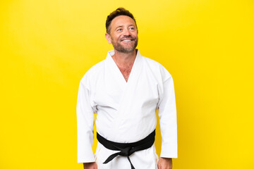 Middle age caucasian man doing karate isolated on yellow background thinking an idea while looking...