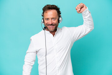 Telemarketer caucasian man working with a headset isolated on blue background doing strong gesture