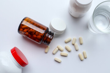 Flat lay of Vitamins, Pills are poured out from the brown glass bottle on white background 