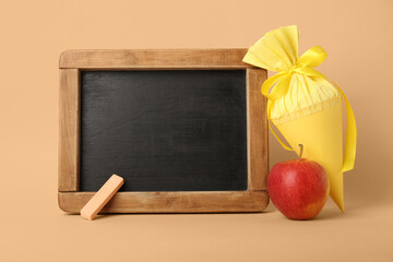 School cone with apple and chalkboard on beige background