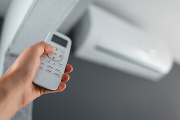 Obraz premium Close-up of male hand using remote control of the air conditioner.