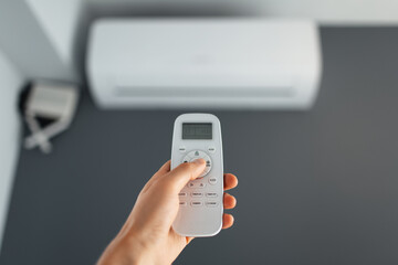 Close-up of male hand using remote control of the air conditioner.