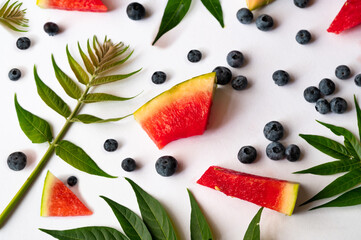 Green leaf, piece of watermelon and blueberry fruit on white.