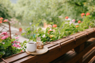 Mug with tea and cinnabon on tray on cozy balcony of wooden cottage.