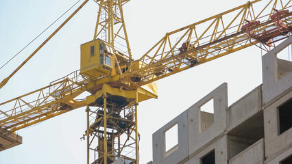 Fototapeta na wymiar Yellow crane on the background of building. White sky background.
