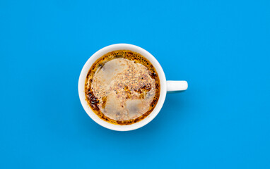 Frothy coffee in a porcelain cup on blue background