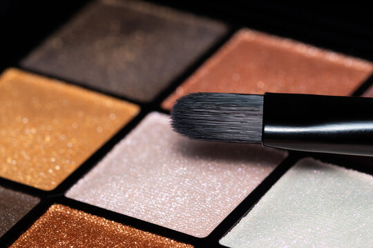 Close up photo of colourful eyeshadow palette with soft brush.