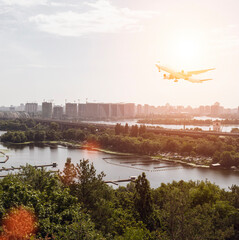 Large passenger plane over the city and nature. Sun light airliner. View of the river below. Transport and travel