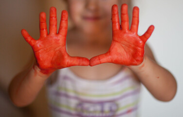 Child's painted hands with red color paint.