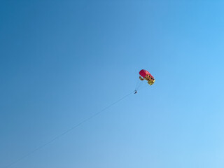 Two people parasailing with a parachute pulled by a boat on vacation at sunset