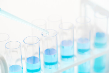 concept of science biology Pipette dropping a sample into a test tube with blue liquid on white background                                 