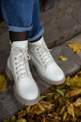 Female legs in a jeans and white fashion boots with laces.