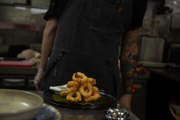 chef prepares deep-fried onion rings in the restaurant kitchen.
