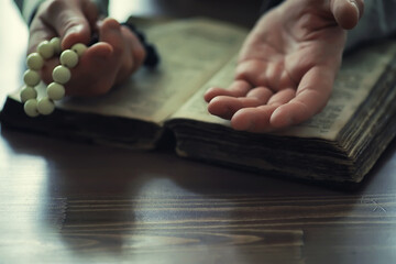 Reading religious literature. A man studies the Koran and sorts out the rosary.