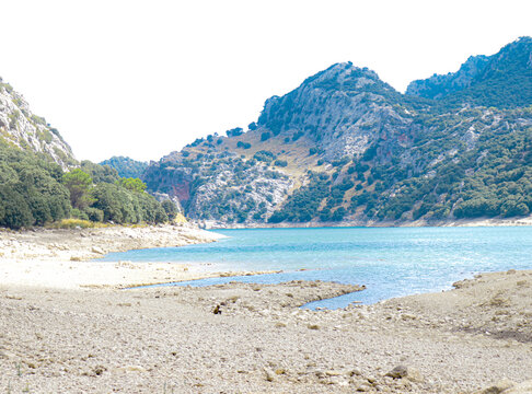 gor blau reservoir with large water capacity located between the mountains of mallorca with a cloudy sky.