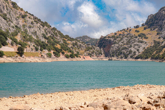 gor blau reservoir with large water capacity located between the mountains of mallorca with a cloudy sky.