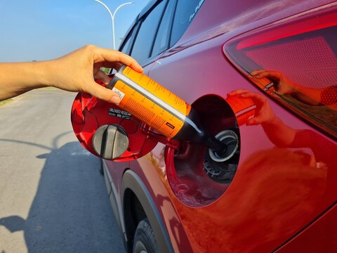 a driver fills a diesel additive into a car's diesel fuel tank to increase the cetane number and lower the sulfur content of biodiesel