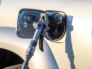 Close-up detail view of fuel autogas pump gun connected with noozle adapter to car tank to refill...