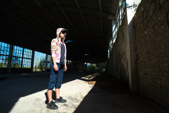 Young female hip hop dancer standing in abandoned building on a sunny summer day
