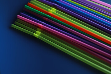 Colorful plastic drinking straws, close up as background. colored tubules for juice and cocktails on black wooden table