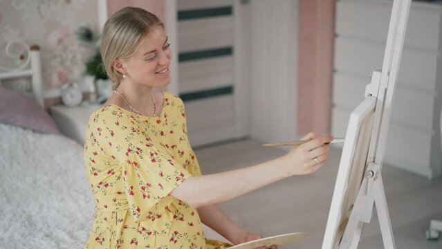 Pregnant woman painting a picture at home