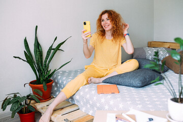 Young woman talking on smartphone from home on video call