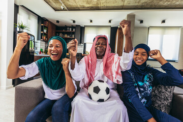 Arab man looking TV at home during a sport event with his family. Watching football game.