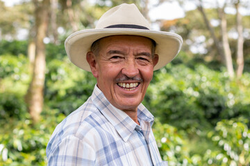 Portrait of an old Colombian peasant man wearing a hat and looking at the camera with a big smile.