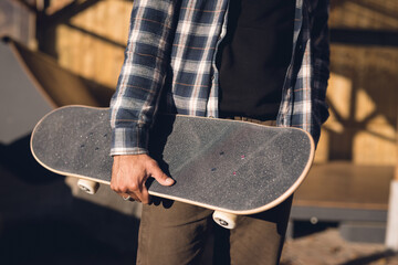 Image of midsection of hispanic man with skateboard in skate park