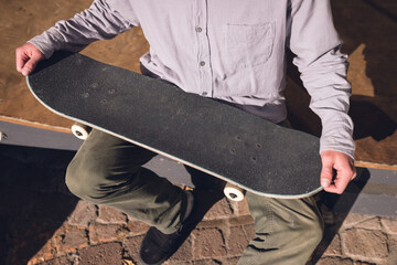 Image of midsection of caucasian man with skateboard in skate park