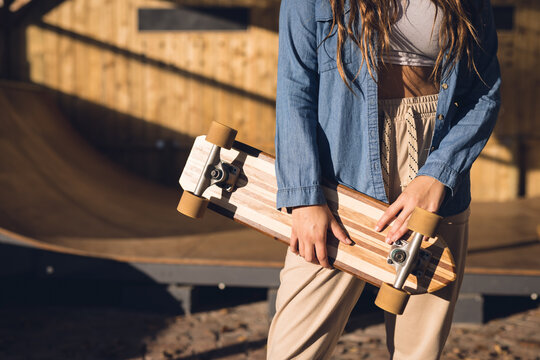 Image of midsection of caucasian woman holding skateboard in skate park