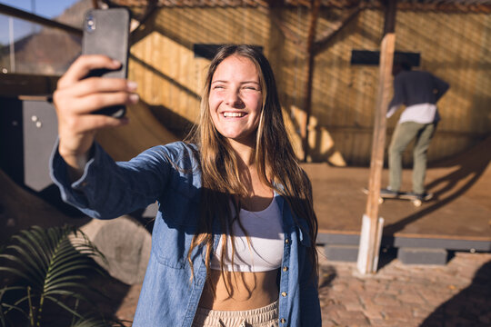 Image of happy caucasian woman taking selfie in skate park