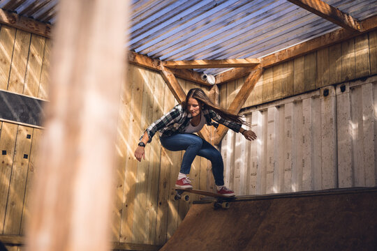Image of caucasian woman jumping on skateboard in skate park - Powered by Adobe