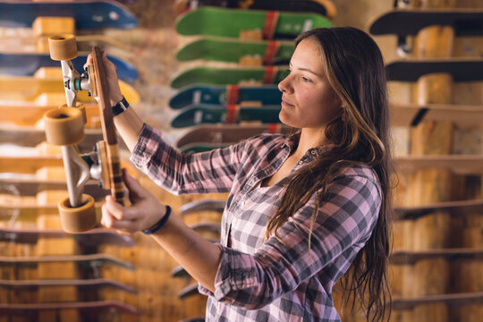 Image of caucasian woman holding skateboard in skate shop